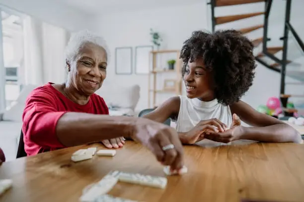 Grandmother and granddaughter playing dominoes together.