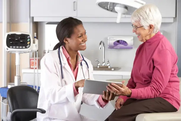 Doctor discusses tablet screen with elderly patient.
