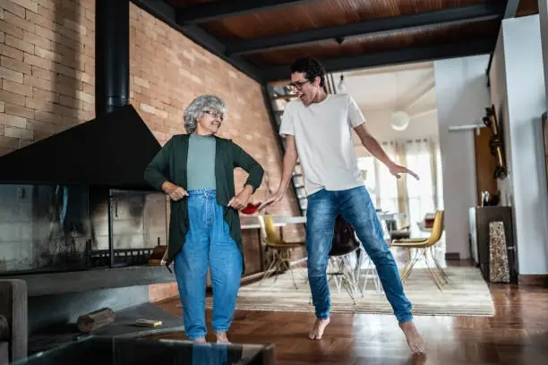Two people dancing joyfully in living room.