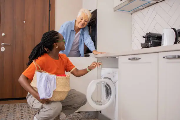 Homecare aid doing laundry for senior citizen.
