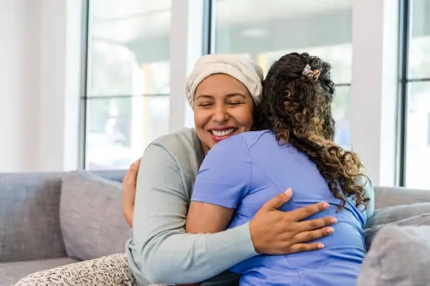 In-home aid hugging care recipient & smiling.